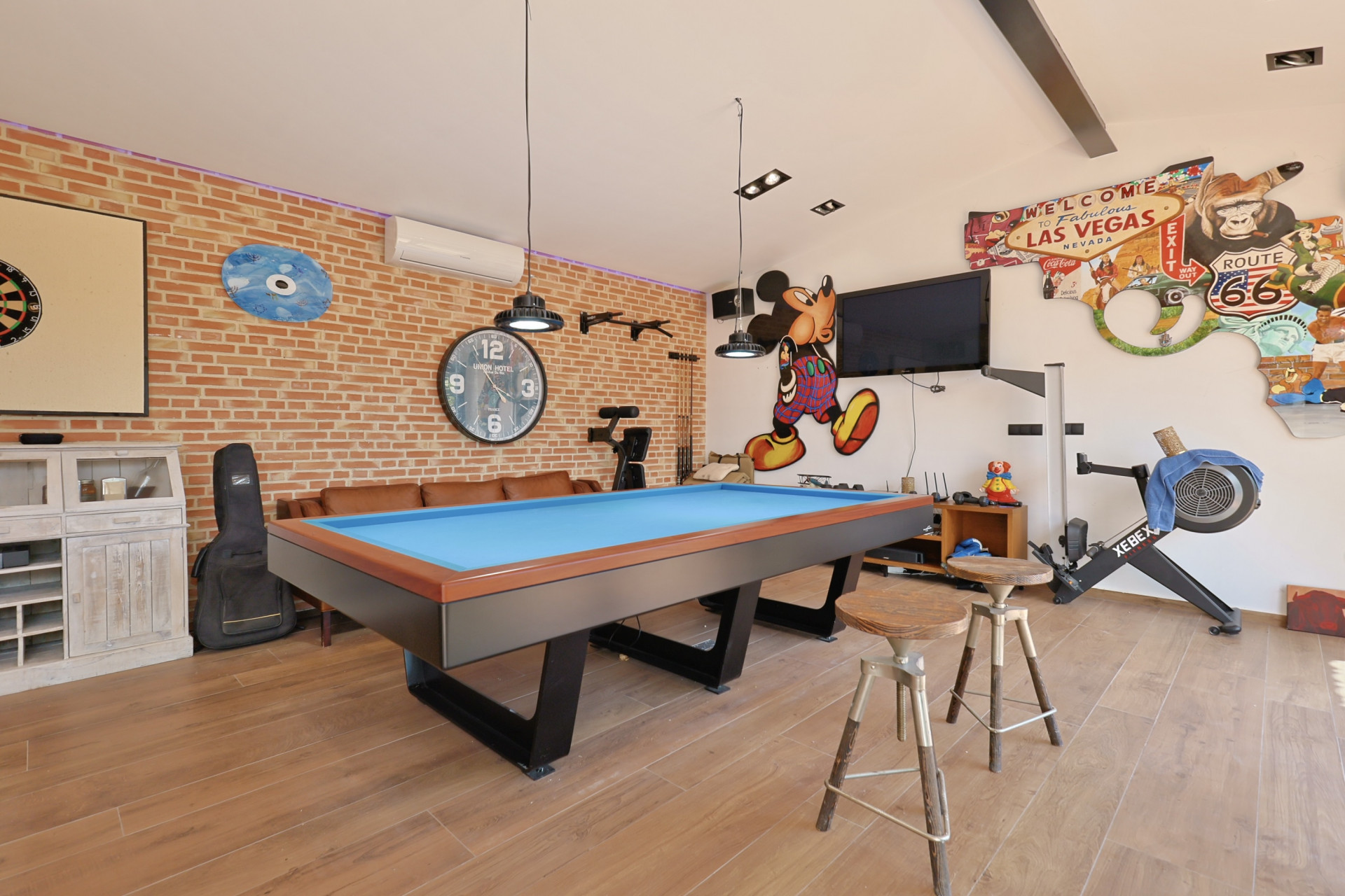 Games room featuring a blue billiard table, exposed brick wall, and themed decorations.