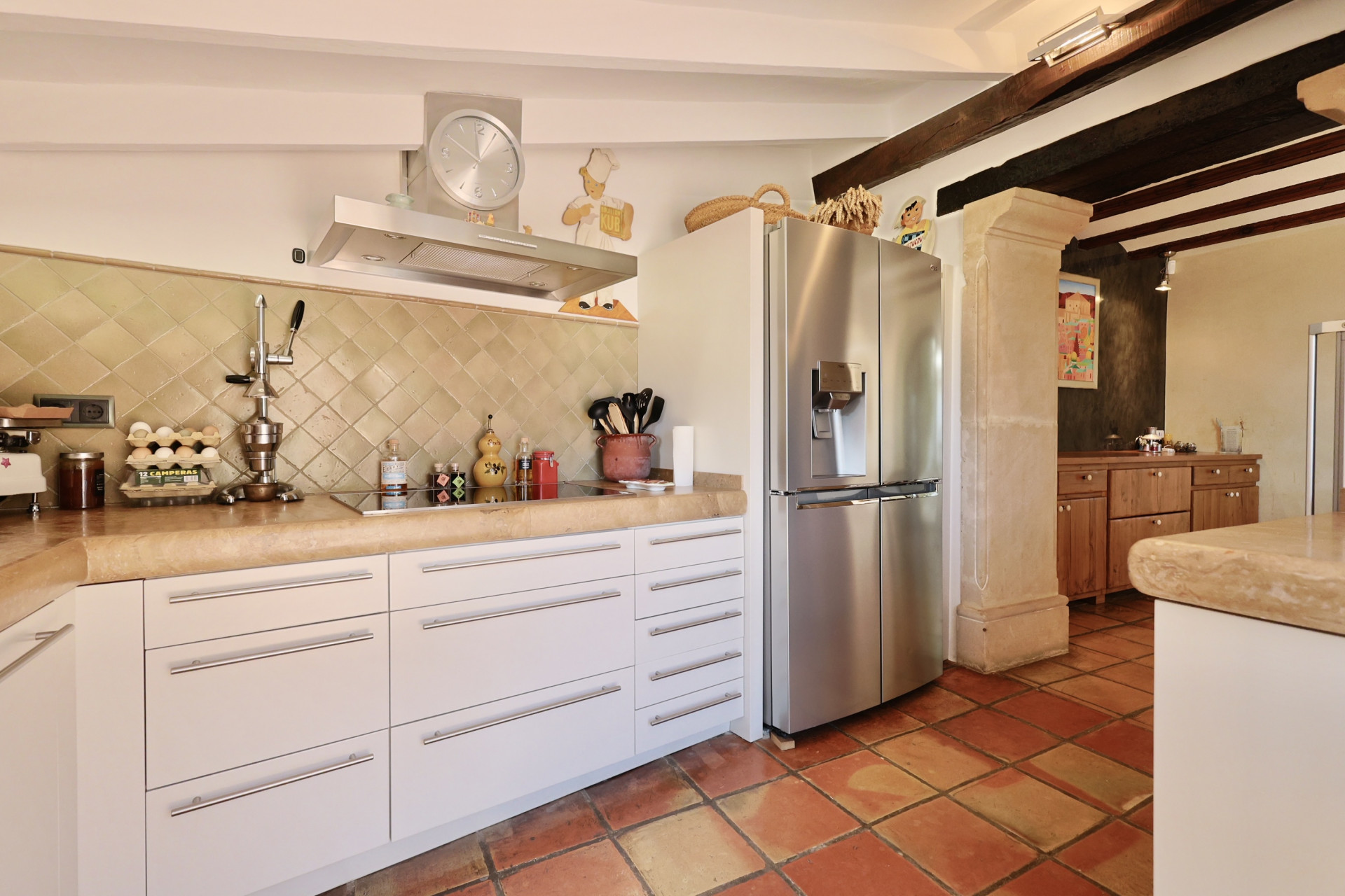 Kitchen detail featuring a stone countertop, rustic tiles, and a stainless steel refrigerator.