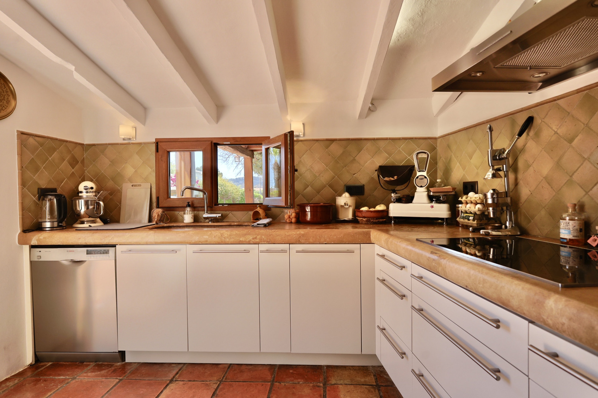 Kitchen detail with stone countertop and rustic tiles. Wooden window with outdoor views.