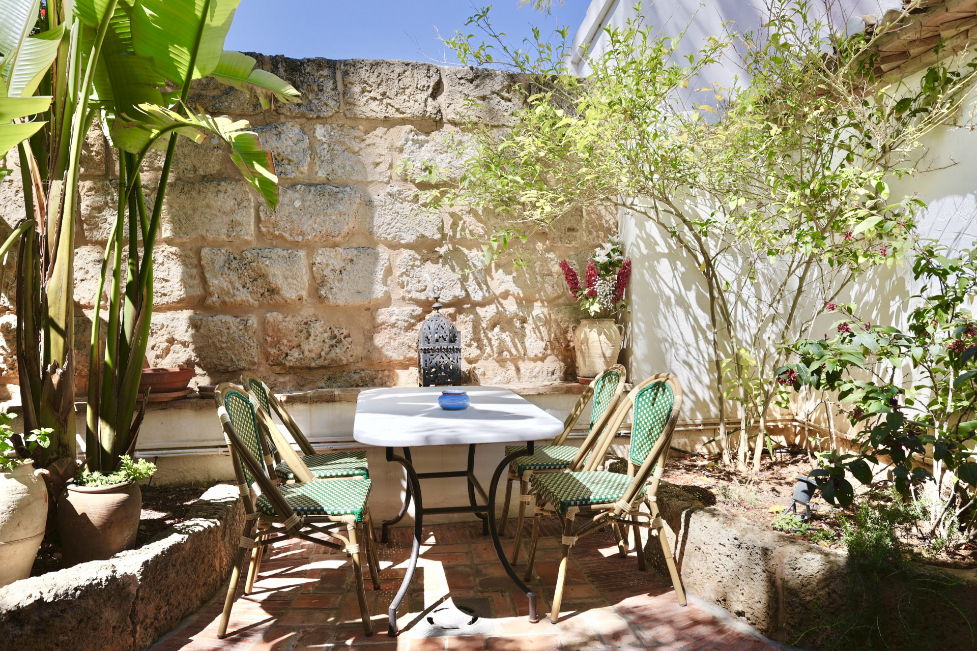 Patio with marble table, wicker chairs, and rustic stone wall. Tranquil, natural ambiance.
