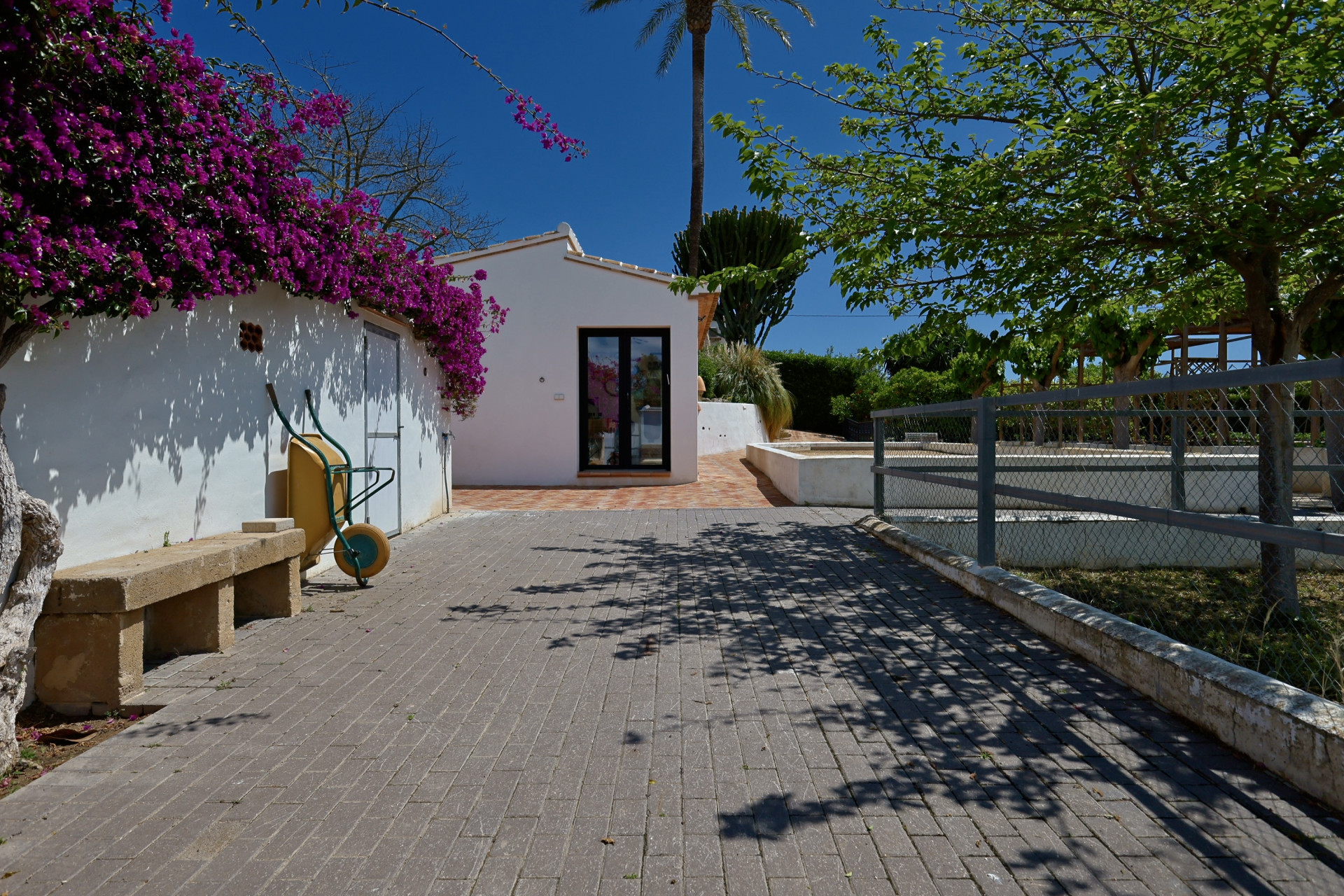 Villa entrance with bougainvillea and stone bench.