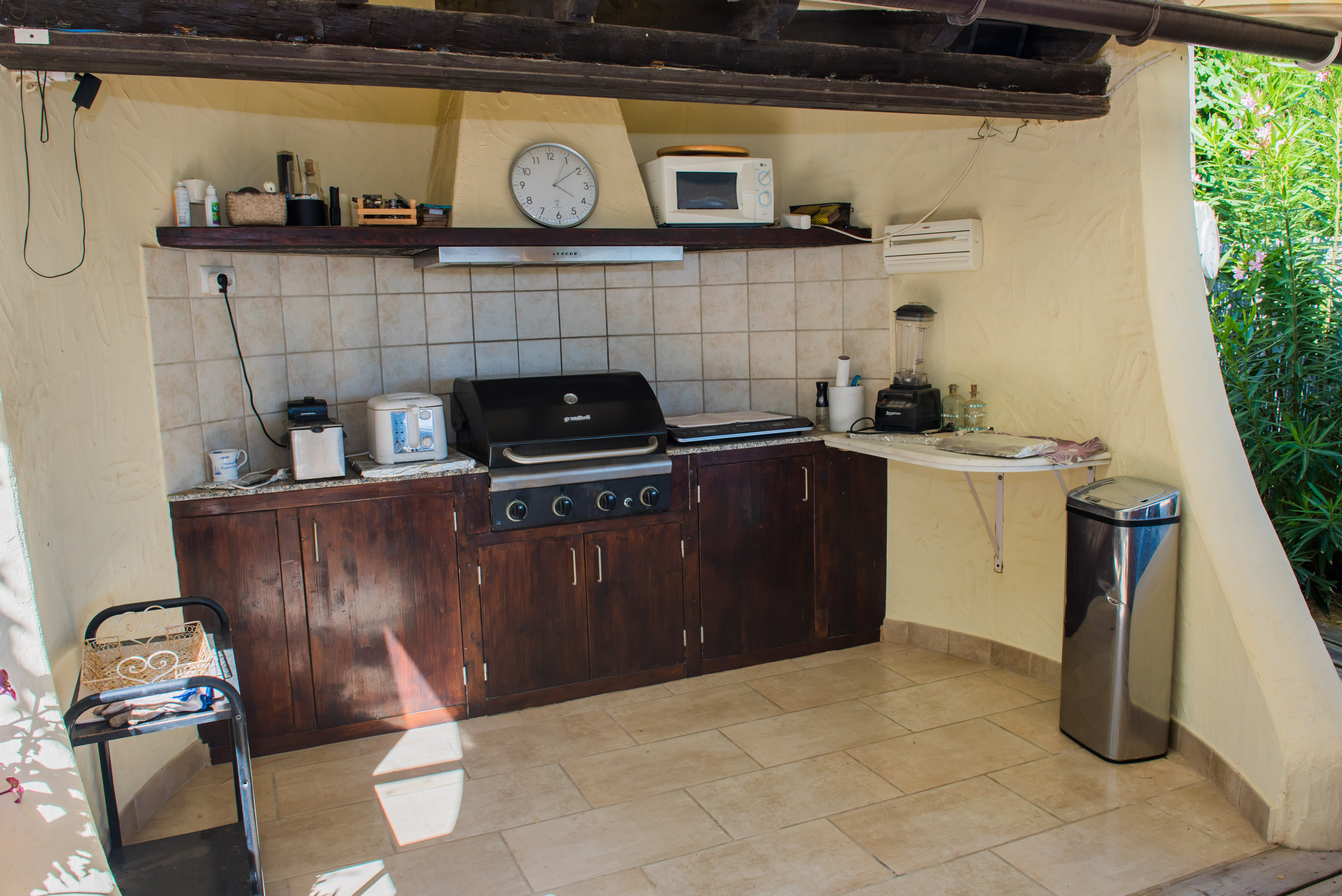 Outdoor kitchen equipped with a grill, dark wood countertop, and appliances. Outdoor kitchen equipped with a grill, dark wood countertop, and appliances.