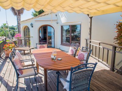 Covered terrace with wood table and upholstered chairs, perfect for enjoying panoramic views of the Mediterranean Sea.