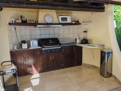 Outdoor kitchen equipped with a grill, dark wood countertop, and appliances.