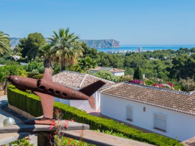 Panoramic view of Jávea from the terrace, featuring an airplane sculpture in the foreground and lush greenery.