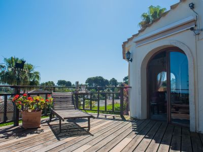 Sunny terrace with wood flooring, a lounge chair, and views of the Mediterranean landscape.