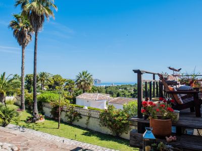 View from the wood terrace with bougainvillea and rustic armchairs overlooking the Mediterranean Sea.