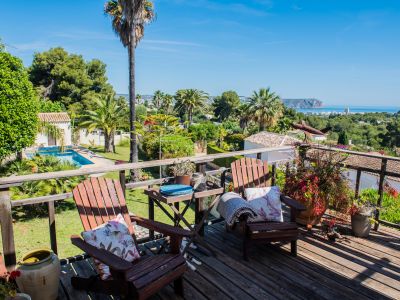View from the wooden terrace with Adirondack chairs, gardens, and panoramic sea views in Jávea.