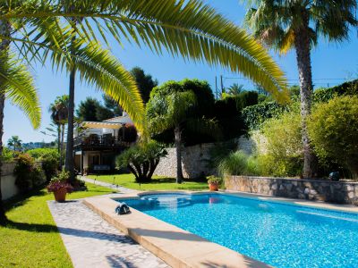 View of the blue-tiled pool and Mediterranean garden with palm trees in Jávea.