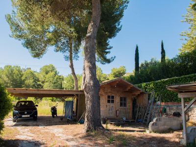 View of the wooden shed and covered garage, surrounded by Mediterranean vegetation and a clear sky.