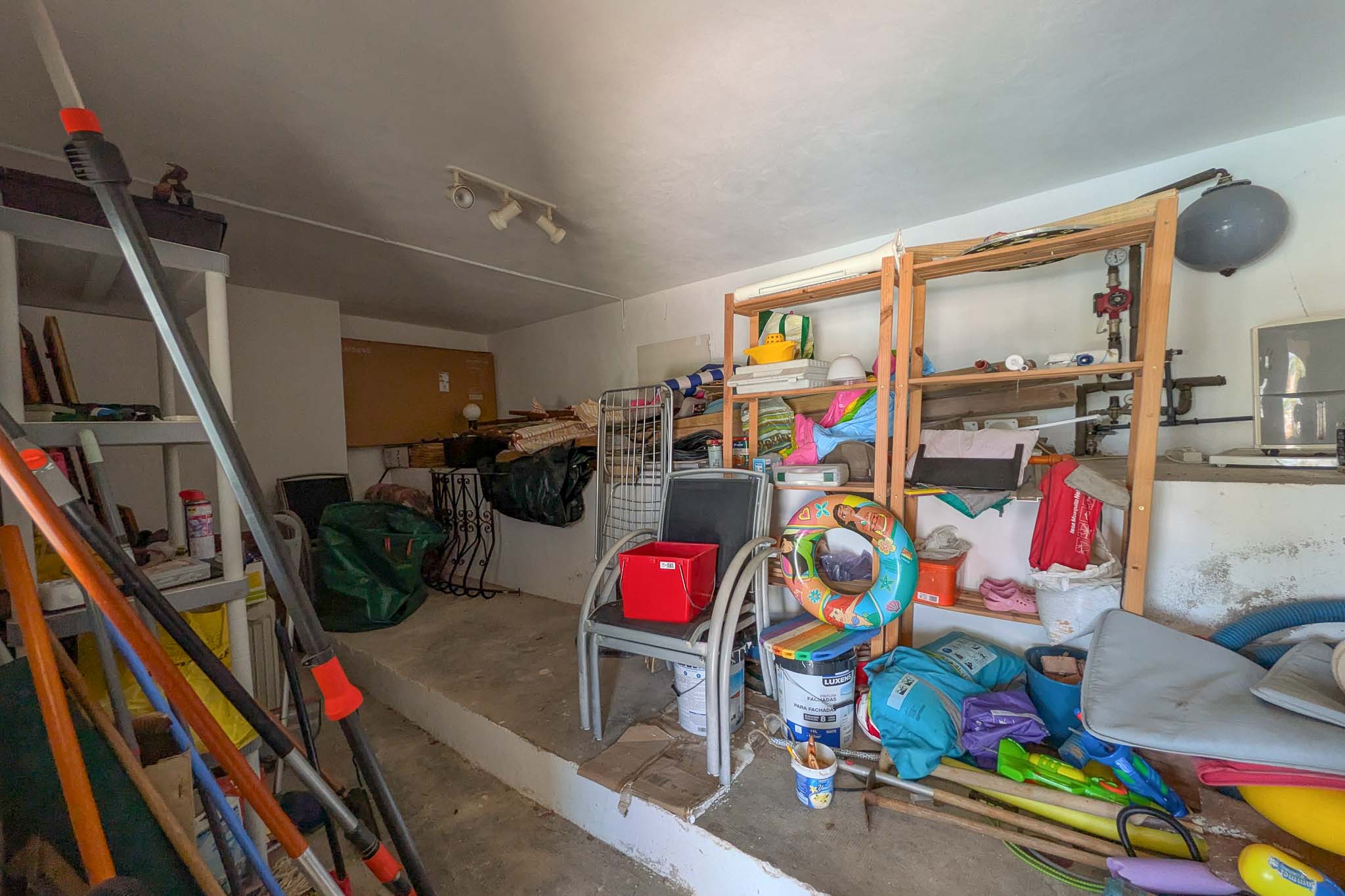 Versatile storage room featuring concrete flooring, wooden shelving units, and ample space for household and garden equipment maintenance.