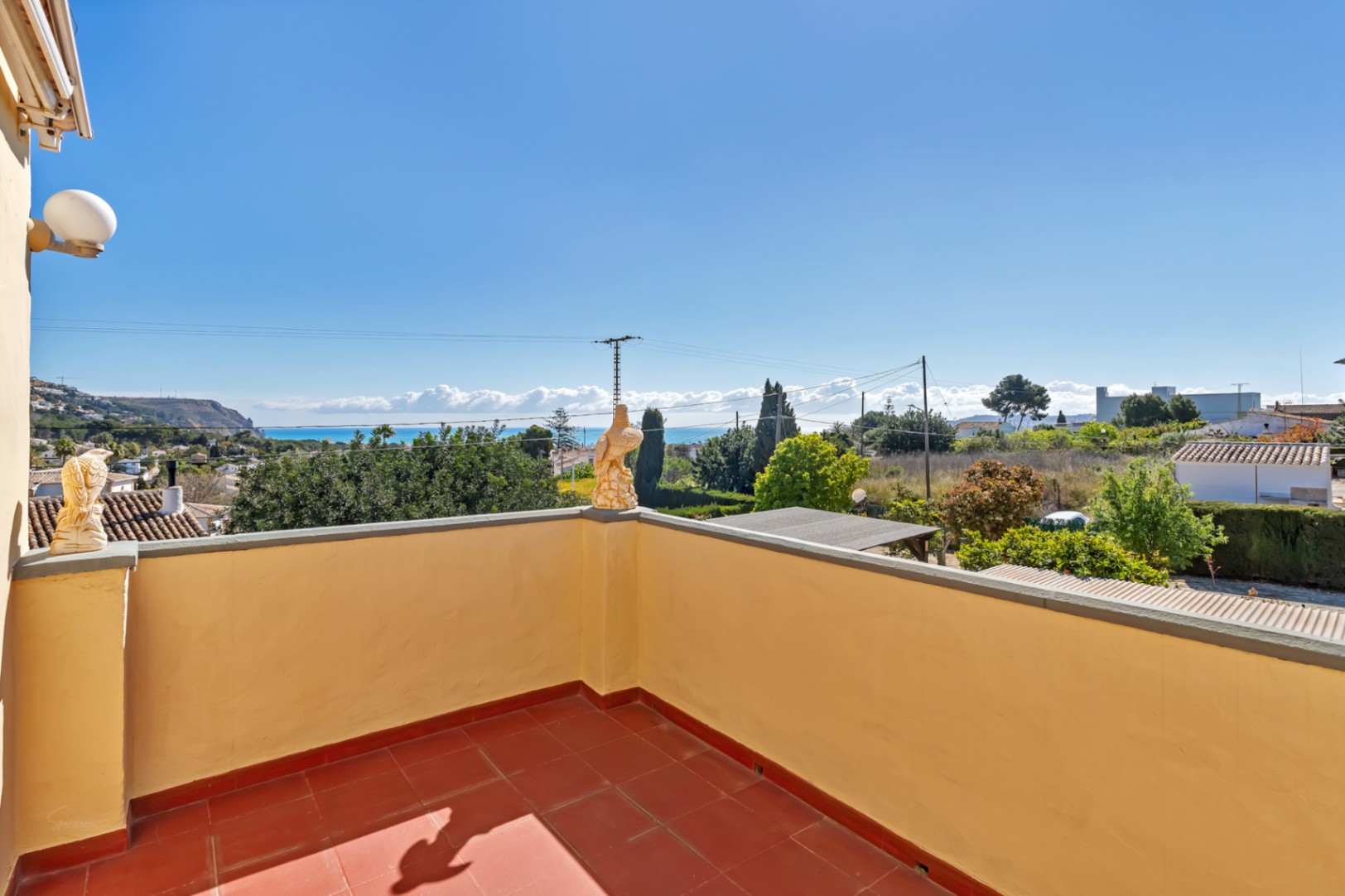 Elevated terrace featuring terracotta tiling and panoramic views of the Mediterranean Sea and the surrounding coastal landscape.