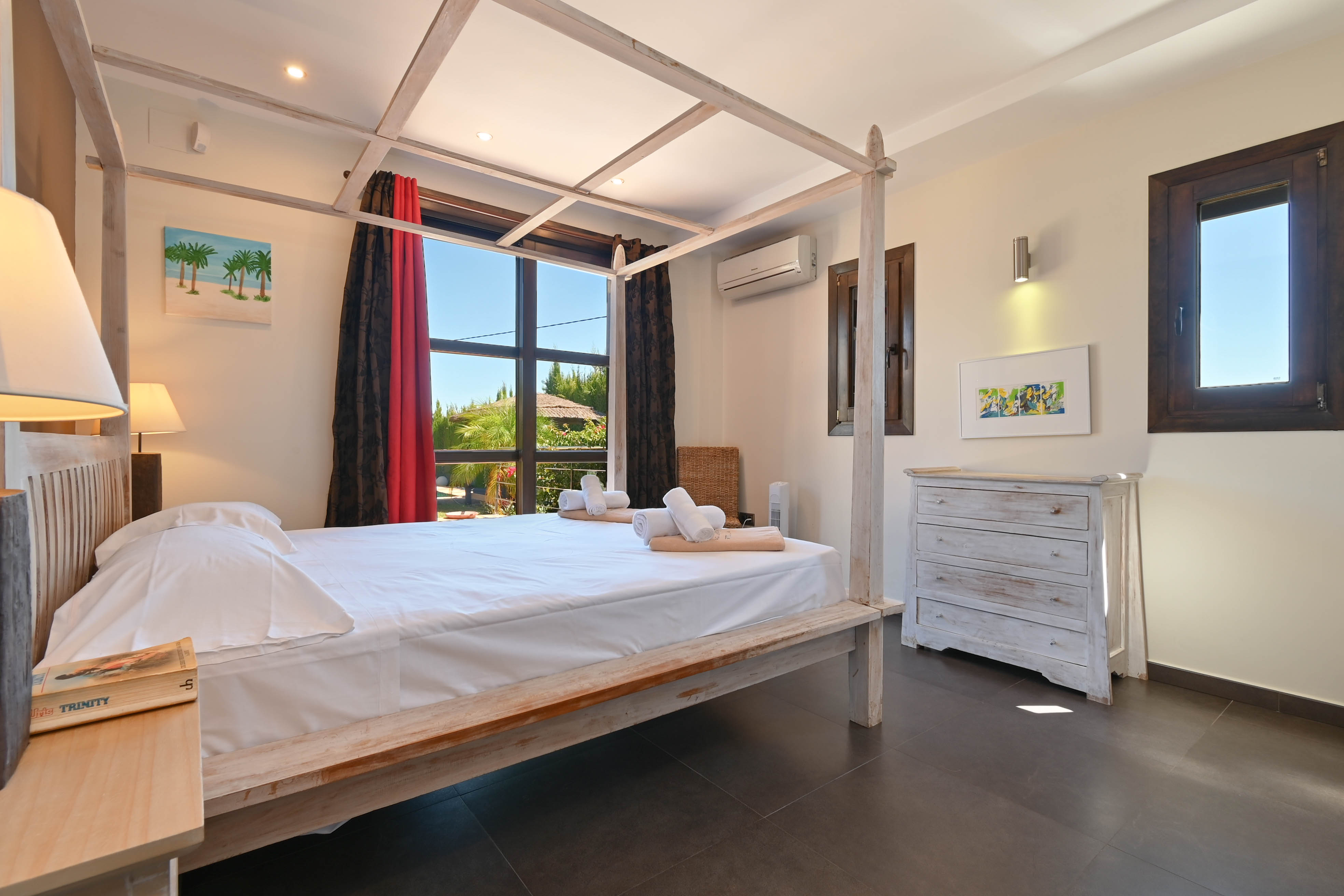 Bright bedroom featuring a light wood canopy bed and a distressed white dresser.