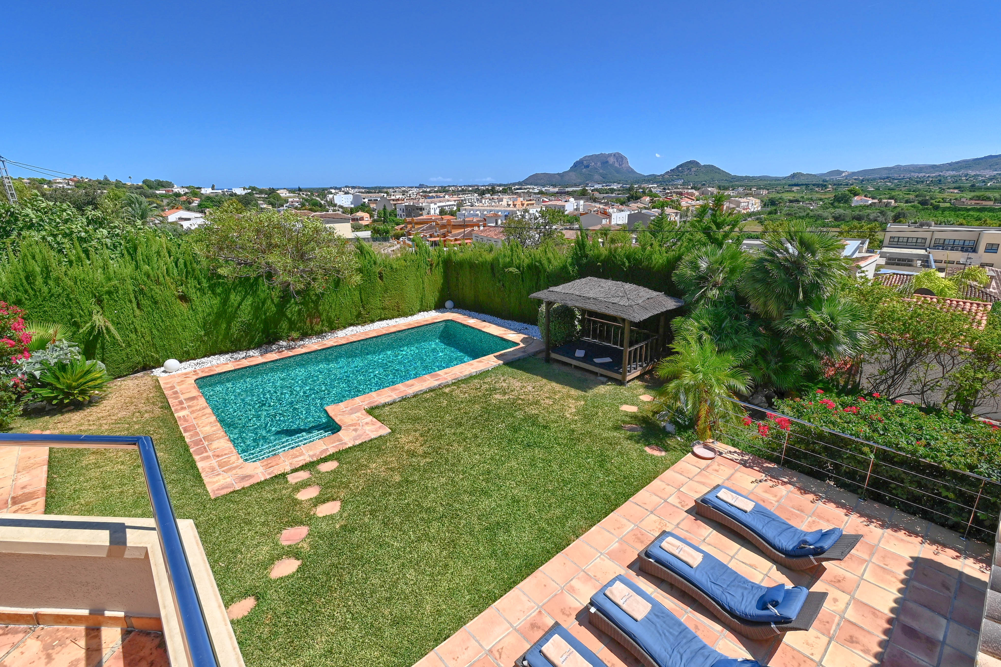 Elevated view of the garden featuring a turquoise pool and thatched-roof gazebo.