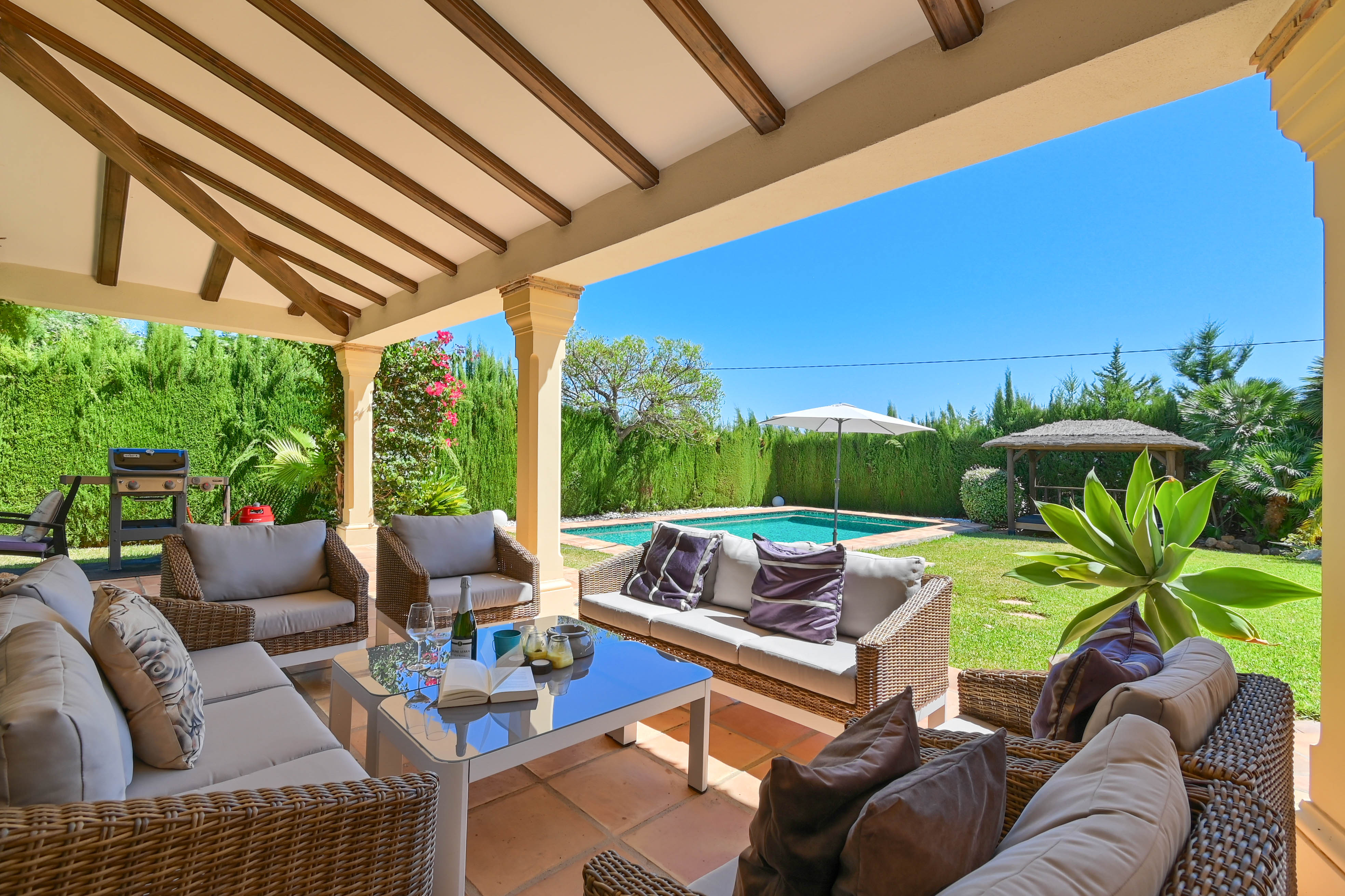 Furnished porch with wicker sofas overlooking the pool and garden.