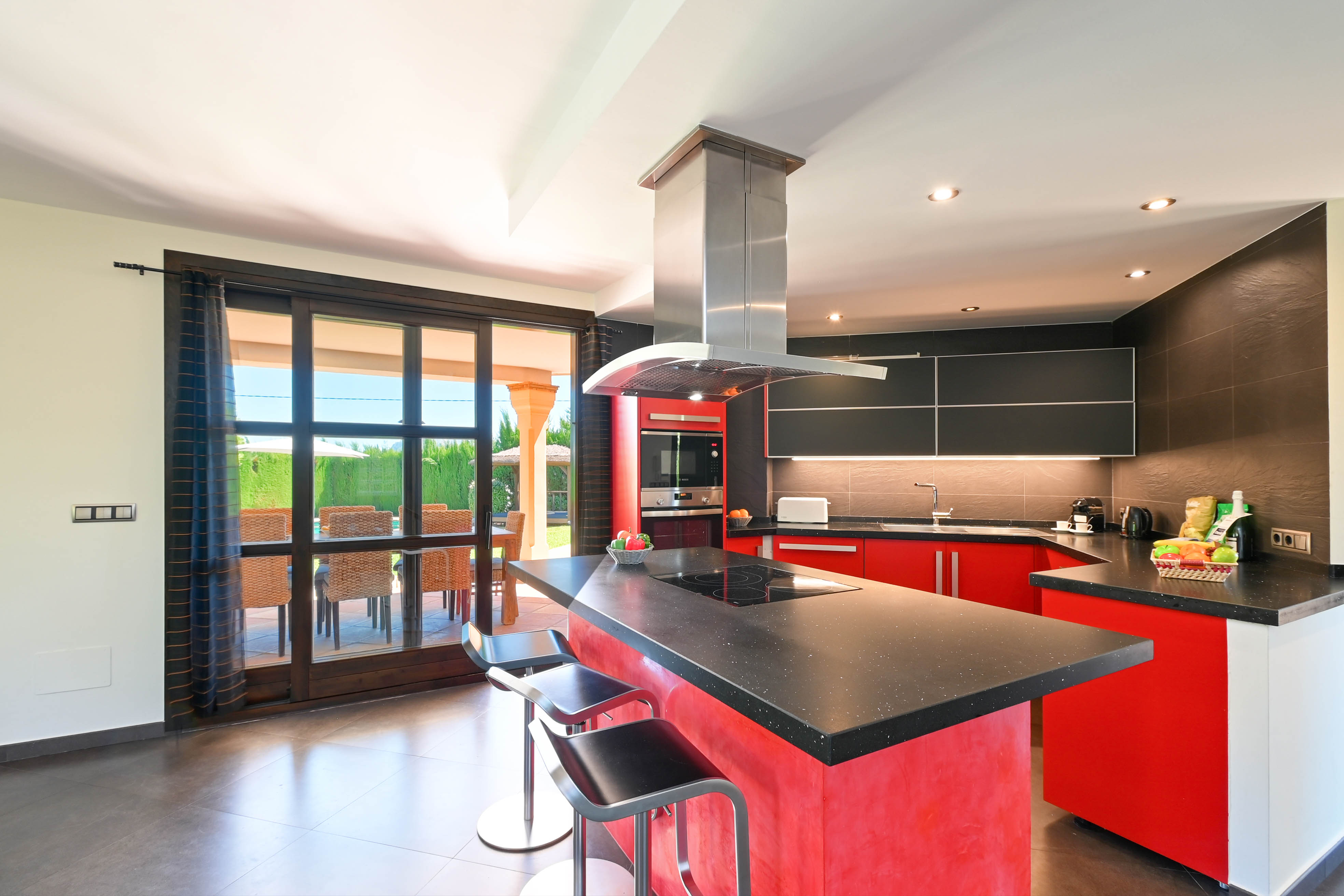 Modern kitchen featuring a central island, black granite countertop, and metal stools.