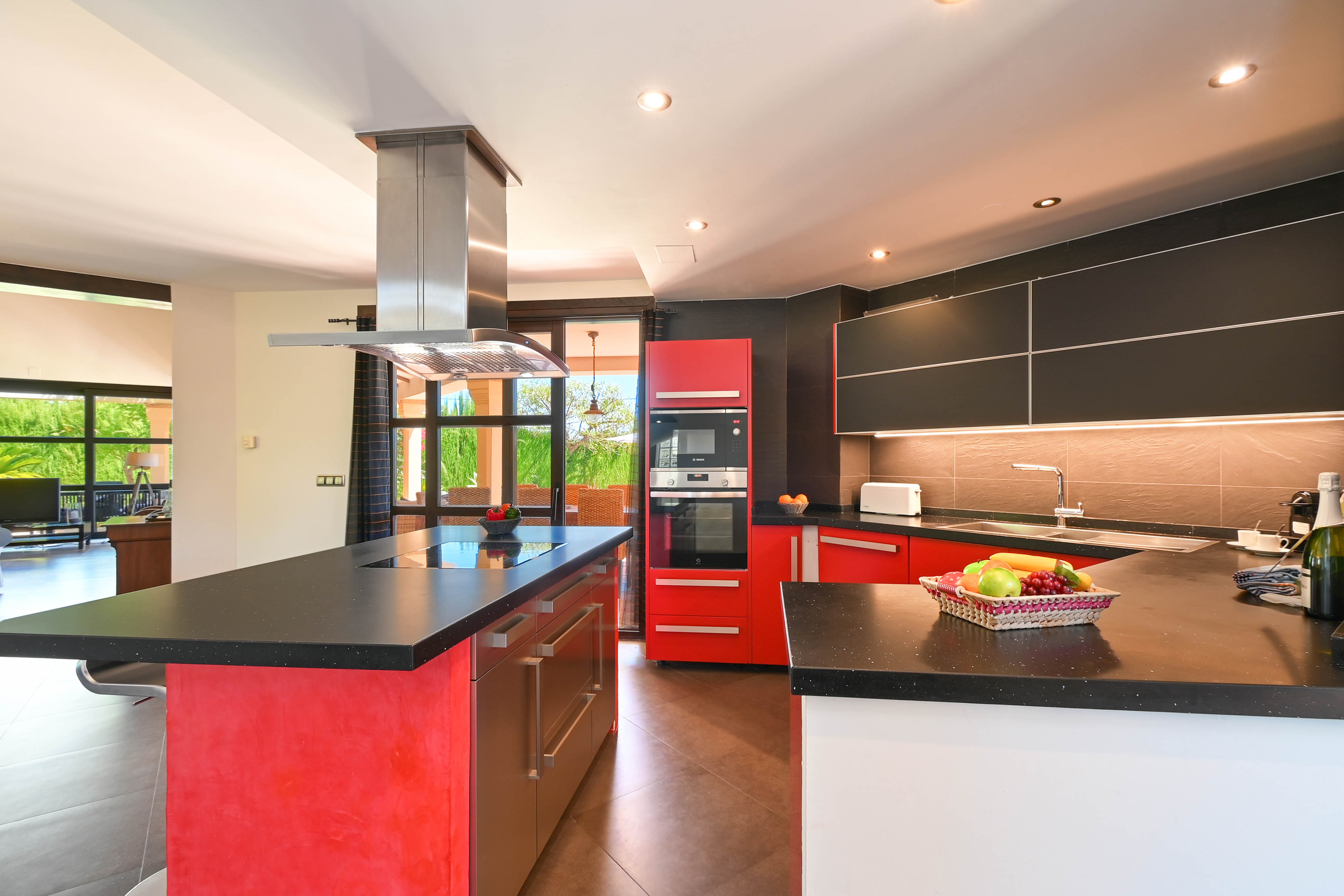 Modern kitchen featuring black granite countertops, red and black cabinetry, and stainless steel appliances.