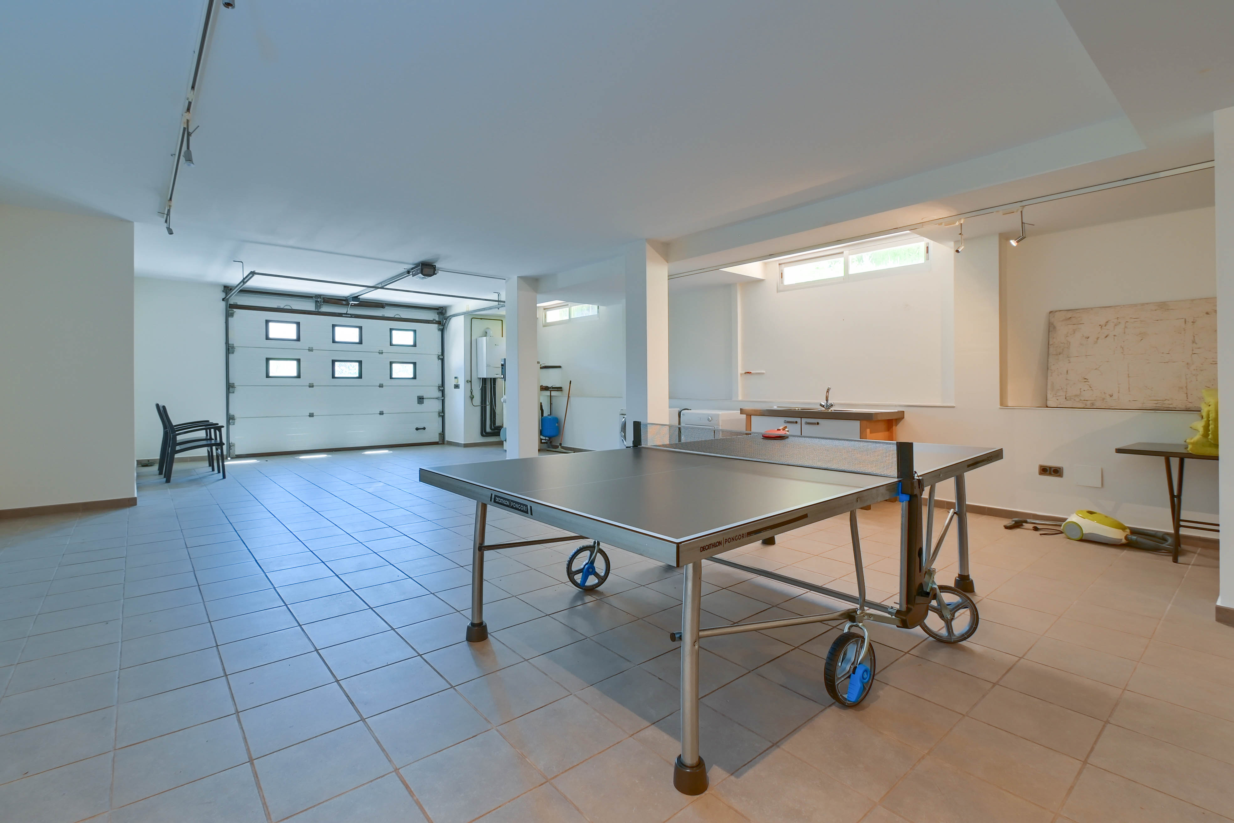 Recreation space featuring a Decathlon Pongori ping-pong table, tiled floor, and garage access.
