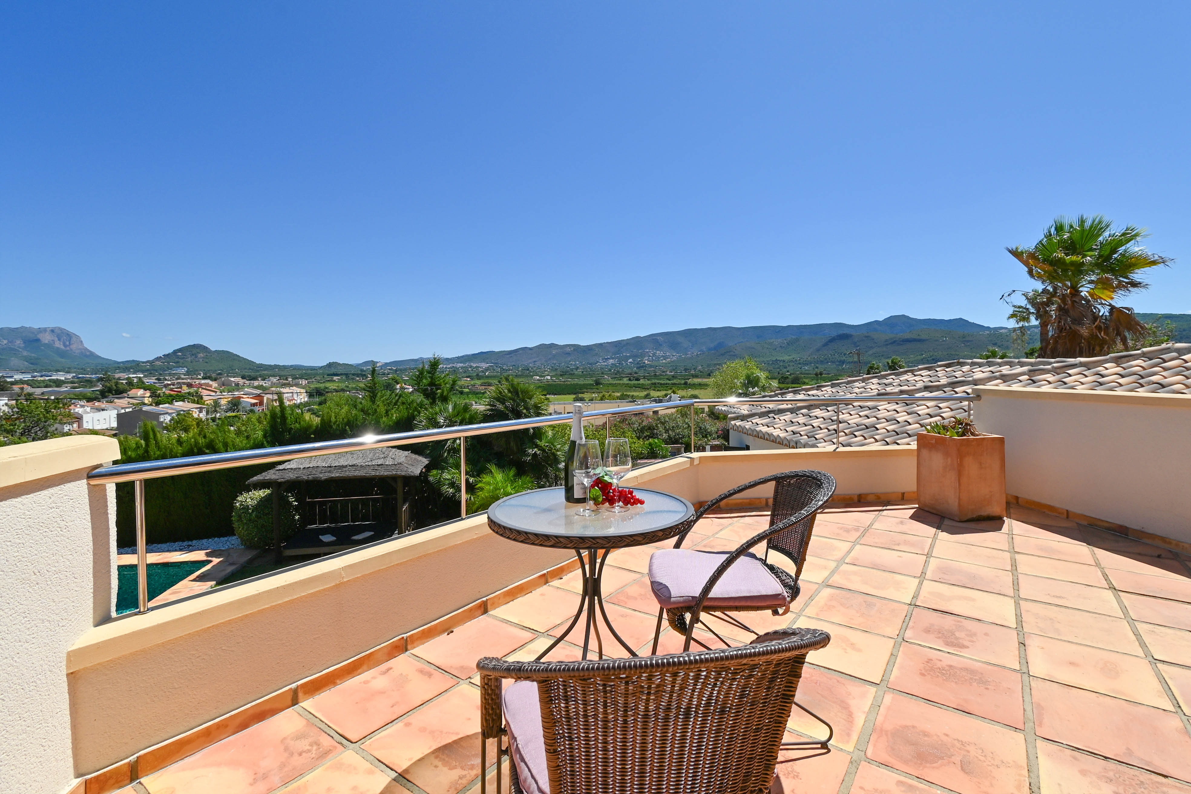 Terrace featuring a glass table, wicker chairs, and views of the valley and mountains.