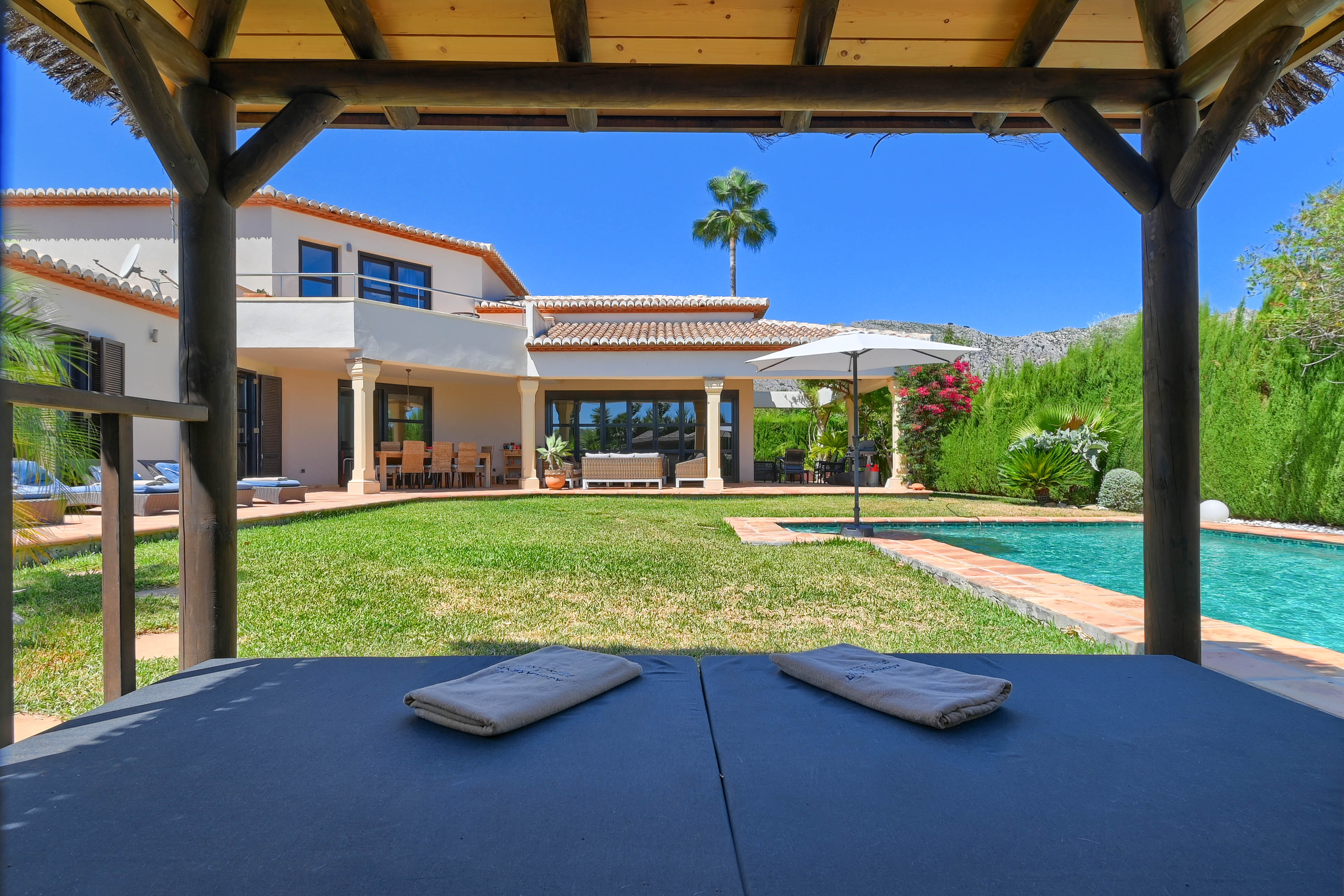 View from gazebo with towels, pool, and lawn garden.