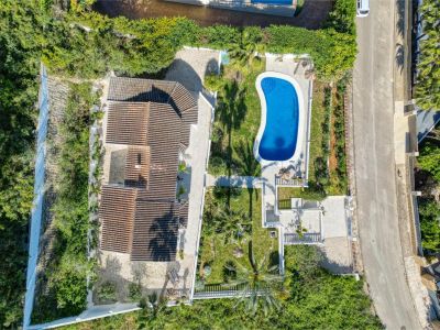 Aerial view of the villa featuring a bright blue pool, surrounded by gardens and lush greenery in Jávea.