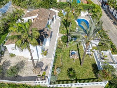 Aerial view of the villa featuring the garden, pool, and terrace. Mediterranean design with white walls and lush greenery.