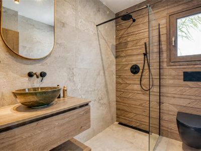 Bathroom detail featuring a stone sink on a wooden countertop and a glass-enclosed shower.