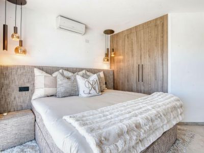 Bedroom featuring a textured headboard, designer pendant lights, and a light wood built-in wardrobe.