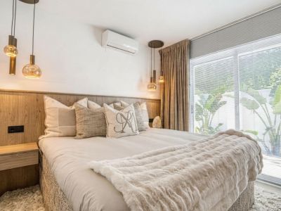 Bedroom featuring a wood headboard, glass pendant lights, and beige curtains beside a window.