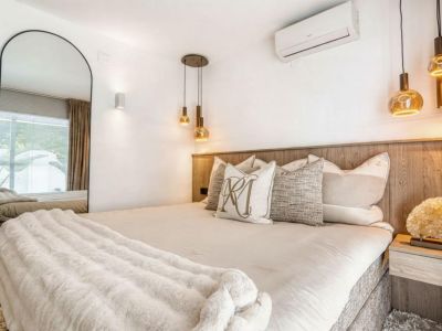 Bedroom featuring a wood headboard, gold pendant lighting, and a full-length mirror.