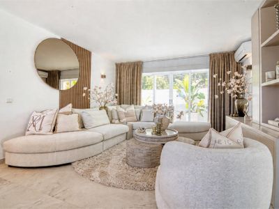 Bright living room featuring a beige sectional sofa, plush rug, and decorative round mirror.