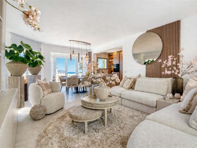 Bright living room featuring neutral decor, plush rug, and access to the dining area with sea views.