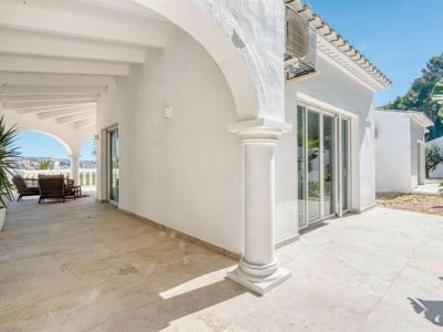 Covered terrace featuring arches and classic columns. Light tile flooring and landscape views.