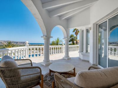 Covered terrace with stone arches, rattan furniture, and panoramic views of the Mediterranean Sea.