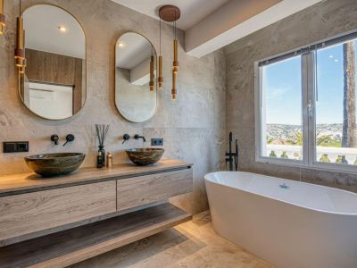 Elegant bathroom featuring stone vessel sinks on a wood countertop, a freestanding tub, and panoramic views.