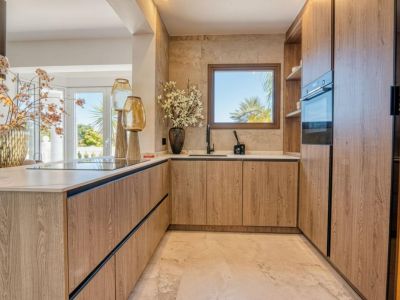 Kitchen detail with light wood cabinets and marble countertop, illuminated with natural light.