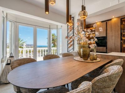 Modern dining area with a wood table, upholstered chairs, and Mediterranean Sea views through large windows.