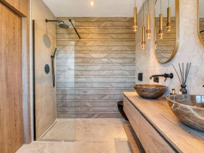 Stylish bathroom featuring stone vessel sinks and a glass-enclosed shower, highlighting the geometric-patterned wall tiles.