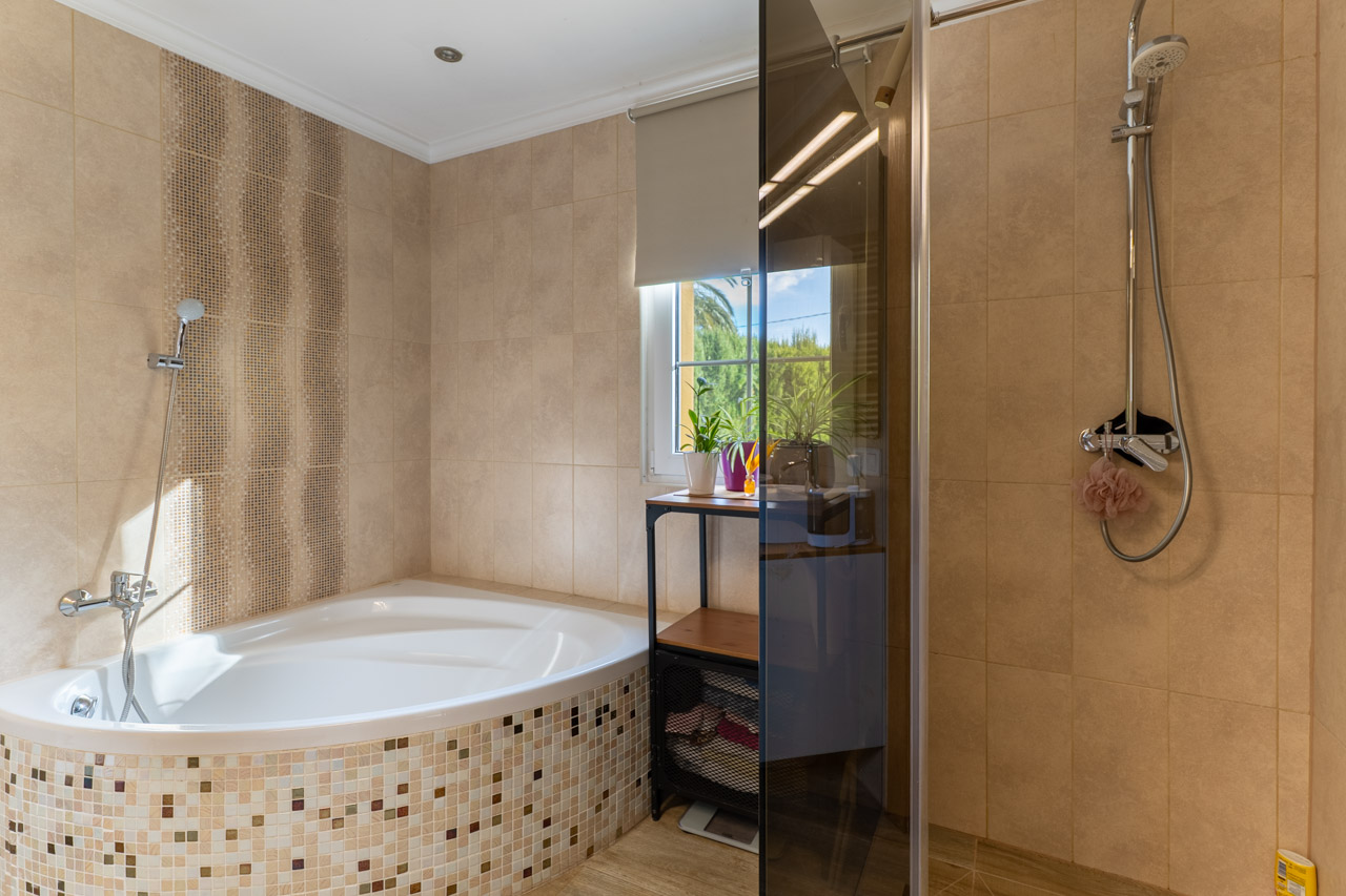 Bathroom detail with mosaic corner bathtub and glass-enclosed shower.