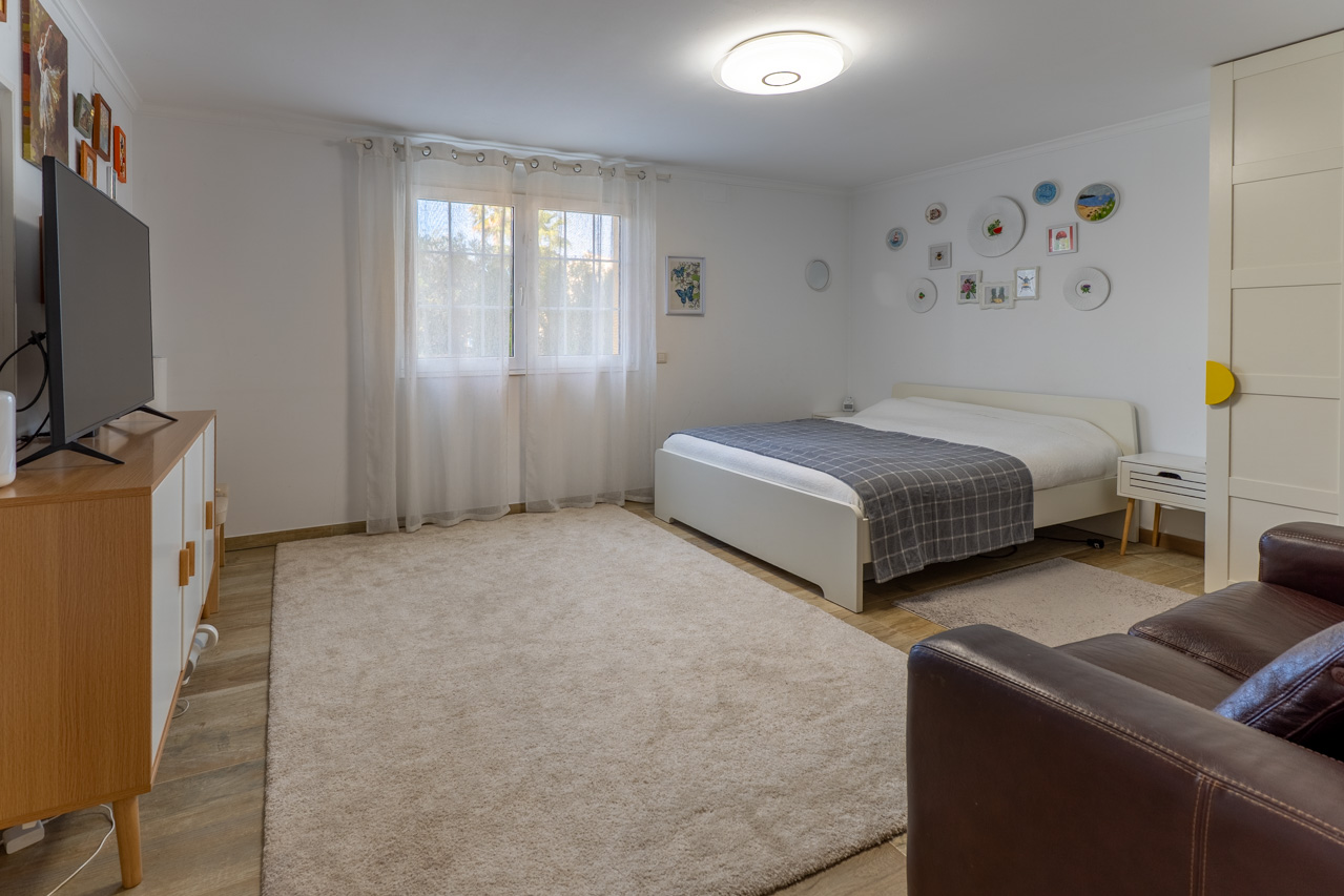 Bright bedroom featuring a white bed, plush rug, and decorative wall art.