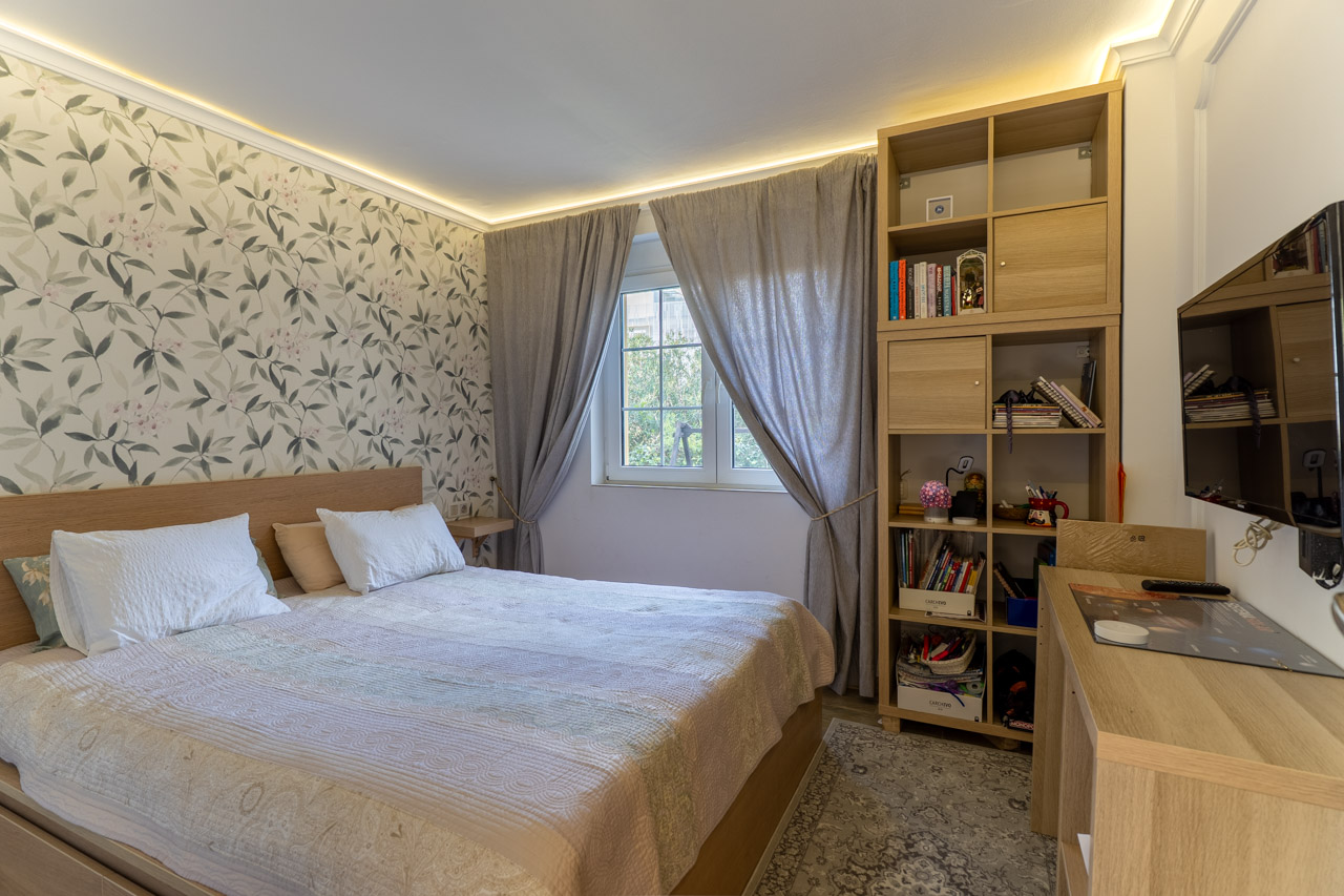 Bright bedroom featuring floral wallpaper, a light wood bed frame, and matching modular shelving.