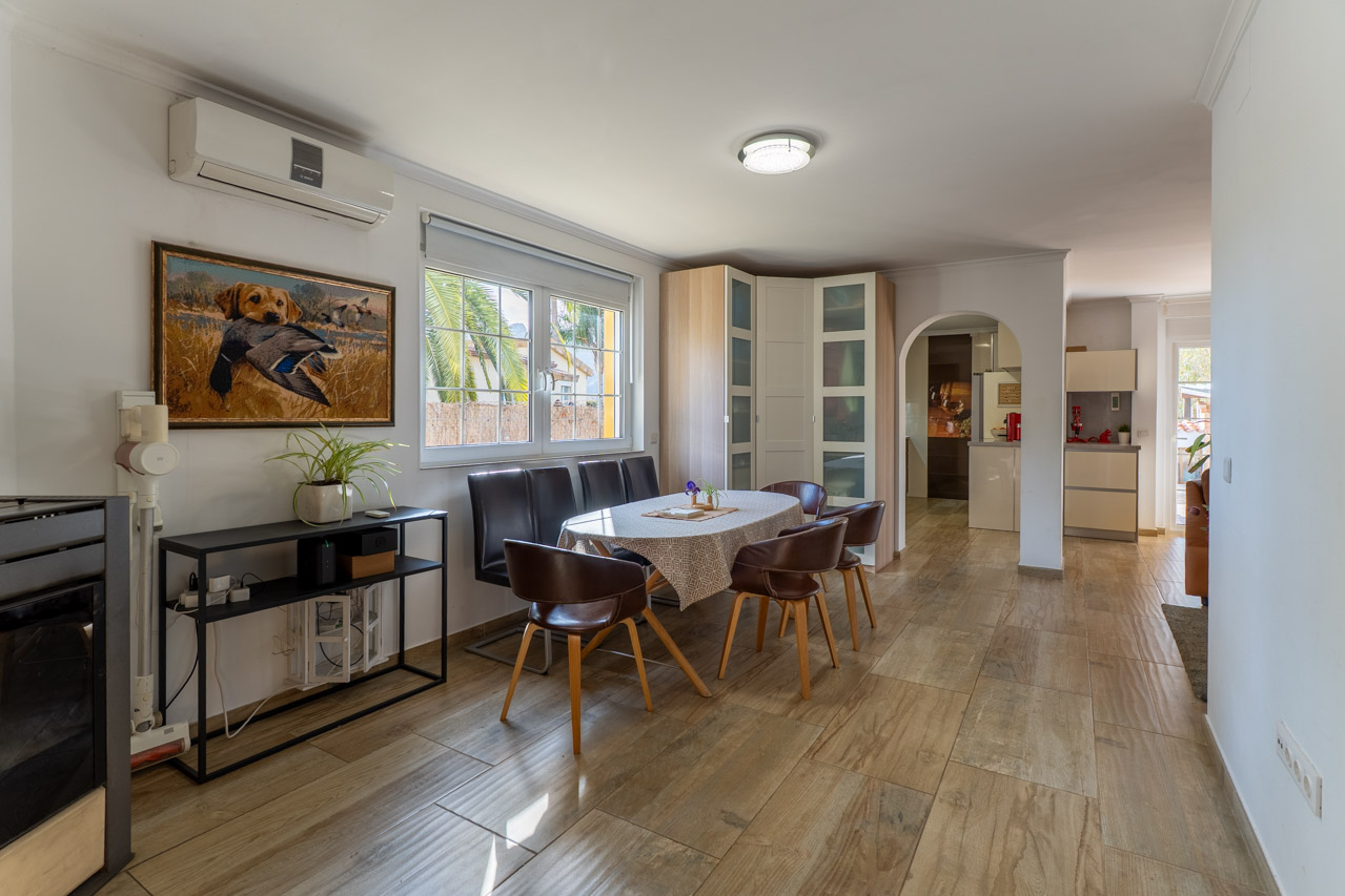 Bright dining room with wood-look flooring, an oval table, and six brown leather chairs.