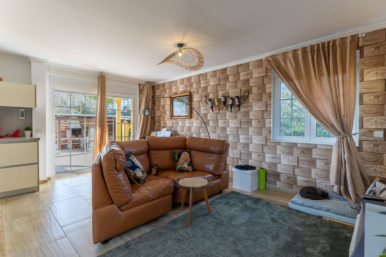 Bright living room with leather sofa, wine crate motif wallpaper, and access to the outdoor terrace.