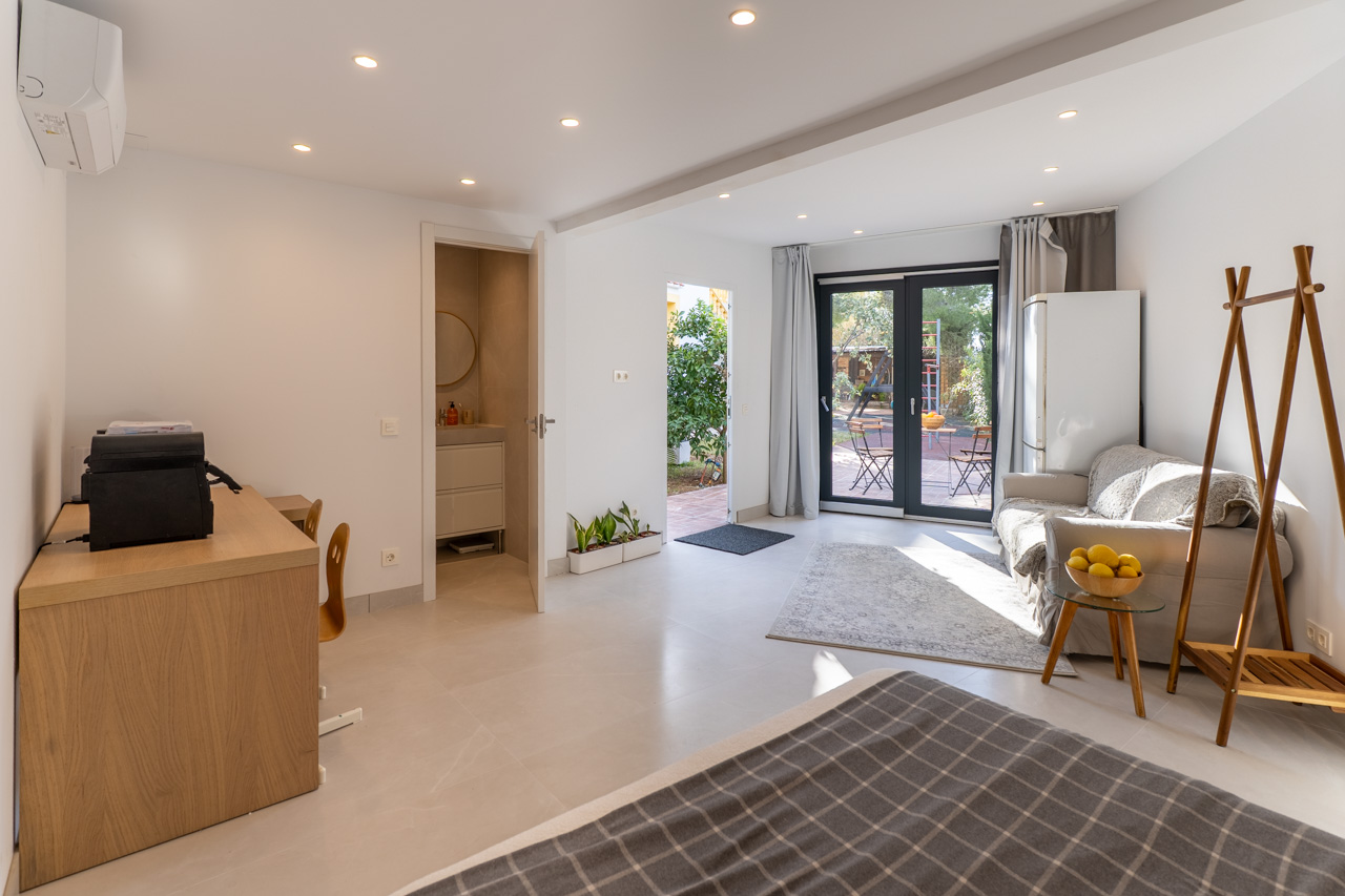 Bright, multi-functional space with garden access, en-suite bathroom, and functional furniture in neutral tones.