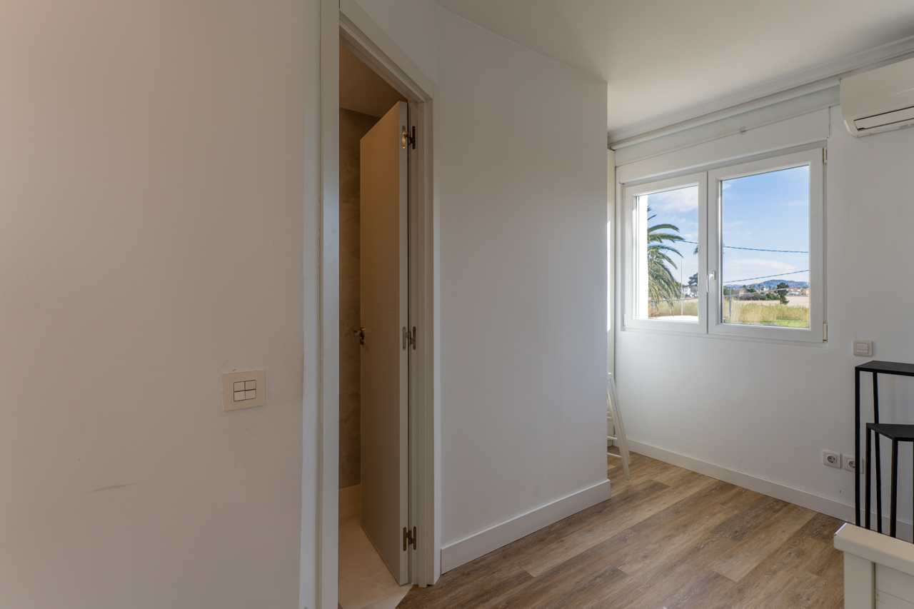Bright room with wood-look flooring and exterior views. Door ajar to the bathroom.