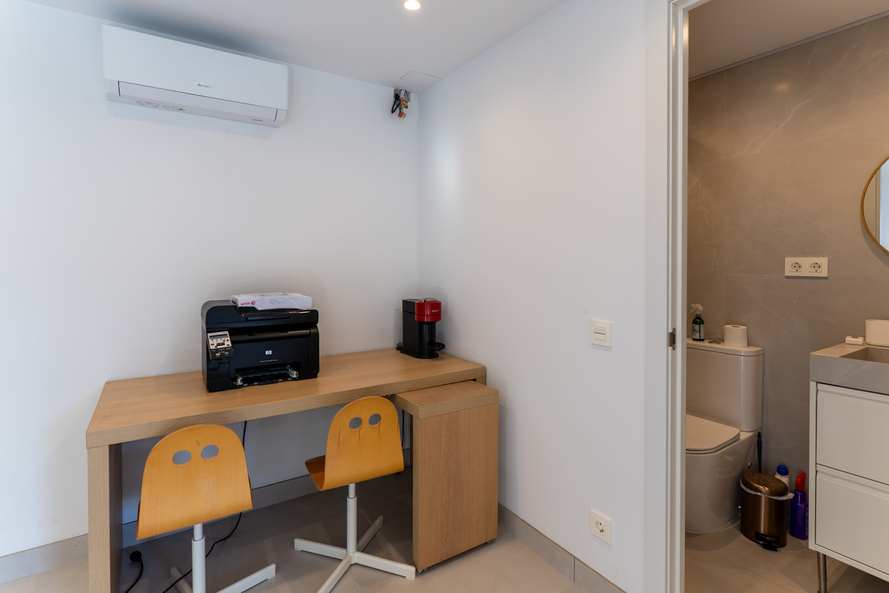 Functional work nook featuring a light wood desk and access to an ensuite bathroom.