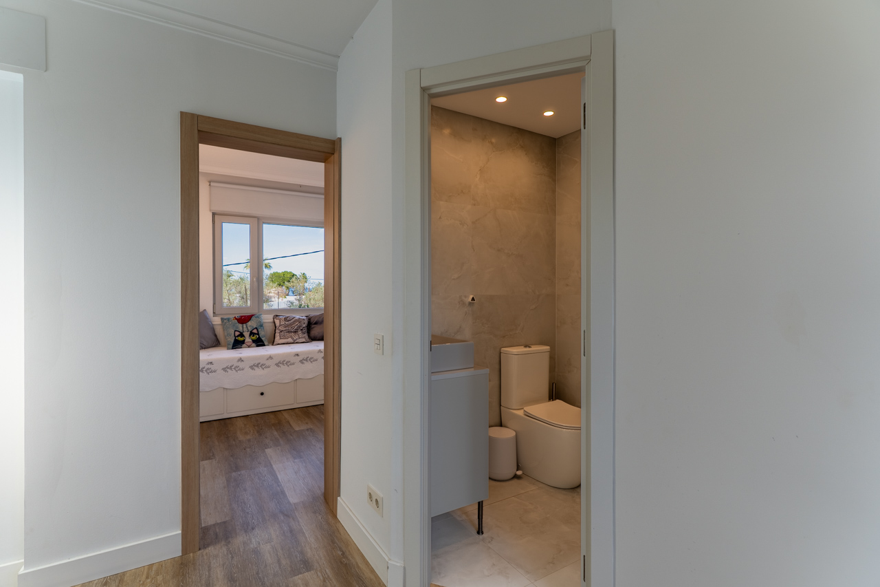 Hallway detail with access to marble bathroom and naturally lit bedroom.