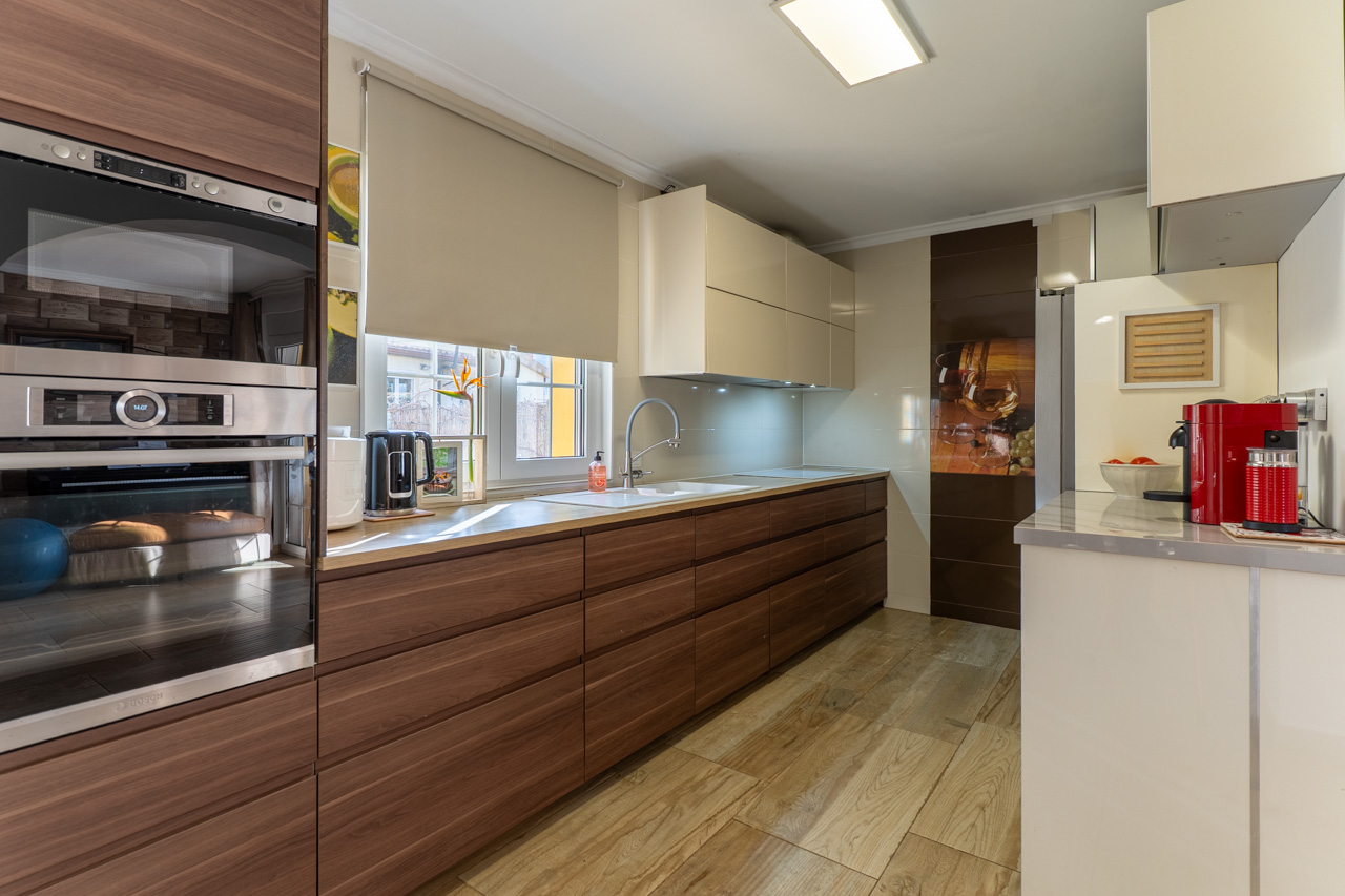 Modern kitchen with wood cabinets, light countertop, and wood-look tile flooring.