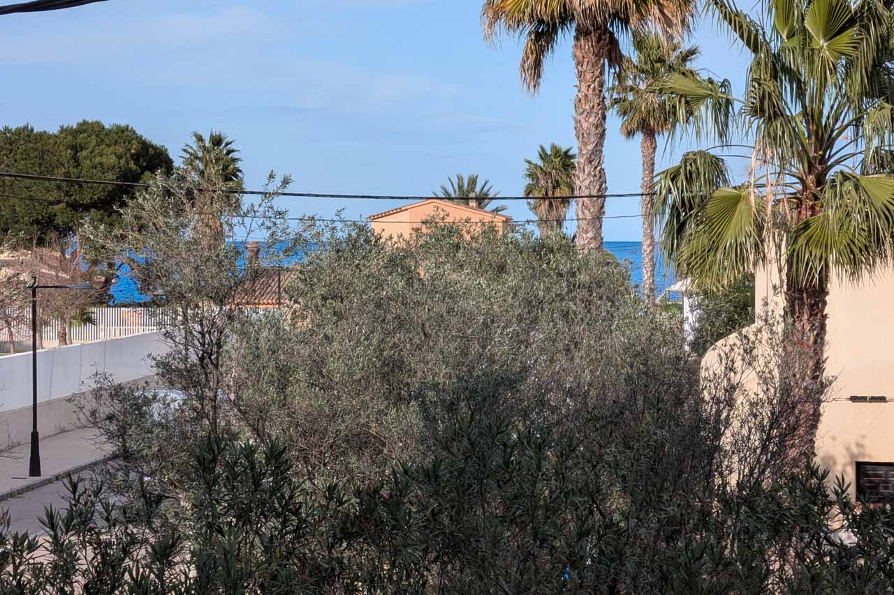 Partial view of the property with Mediterranean vegetation and the sea in the background.