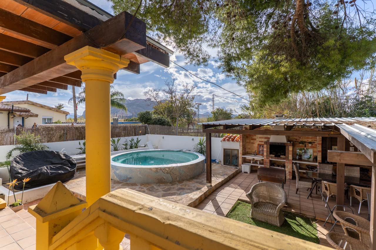 View of the pool area with covered barbecue, from the terrace with yellow railing.